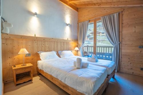 a bedroom with a large white bed with a window at Appartement Corniche - MultiPass in Les Gets