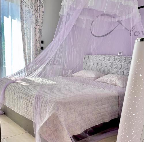 a purple bedroom with a bed with a mosquito net at Theros Lux Apartment in Émbonas