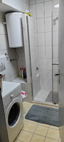 a bathroom with a shower and a washing machine at Apartman Ograde in Bosanski Novi