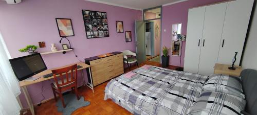 a bedroom with purple walls and a bed and a desk at Apartman Ograde in Bosanski Novi