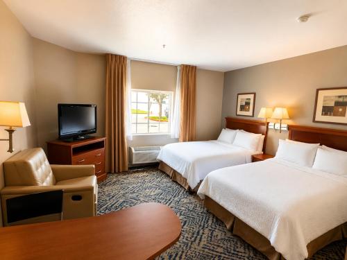 a hotel room with two beds and a television at Candlewood Suites Houston Westchase - Westheimer by IHG in Houston