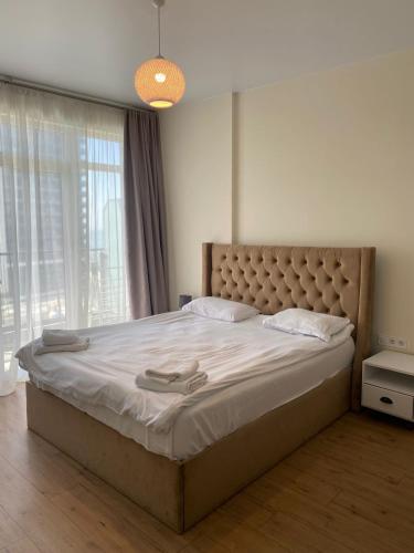a bedroom with a large bed with a large window at Coastal Breeze Apartment in Batumi