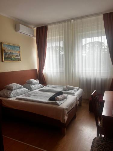two beds in a bedroom with a window at Áldos Panzió in Farád