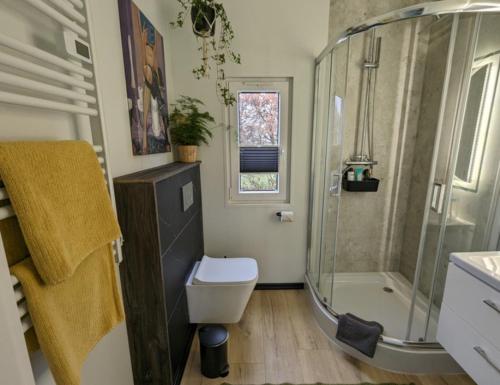 a bathroom with a shower and a toilet and a sink at Tinyhouse Nelson in Papenburg
