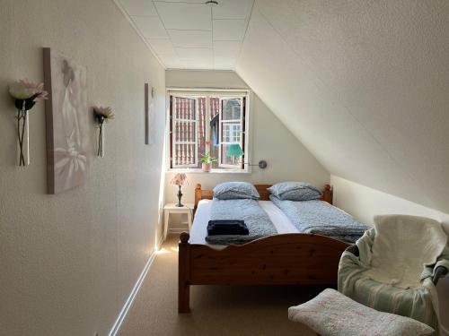 a bedroom with a bed and a chair and a window at Boots and Bikes B&B in Neksø