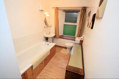 a bathroom with a tub and a toilet and a sink at Cove Cottage Ellary in Lochgilphead