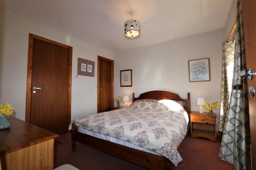 a bedroom with a bed and a table and a window at Cove Cottage Ellary in Lochgilphead