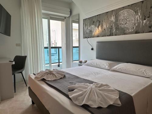 ein Schlafzimmer mit Bett, Schreibtisch und Fenster in der Unterkunft Hotel DOLCEVITA Park & Beach included in Lido di Jesolo