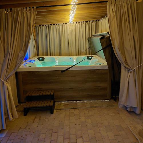a bath tub in a room with curtains at Pájer Plázs & Resort in Gyomaendrőd