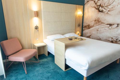 a hotel room with two beds and a chair at ibis Styles Chinon in Chinon