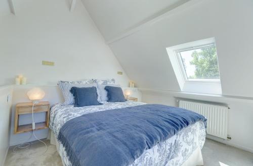 a white bedroom with a bed with blue sheets and a window at Be My Guest Champagne in Gueux