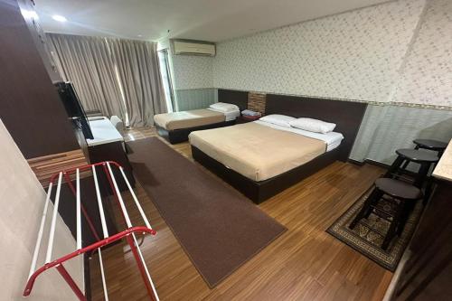 a small room with two beds and a television at Ain Studio Apartment in Kota Bharu