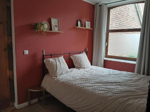 a bedroom with a bed with red walls and a window at Sur l'Oneux in Hotton