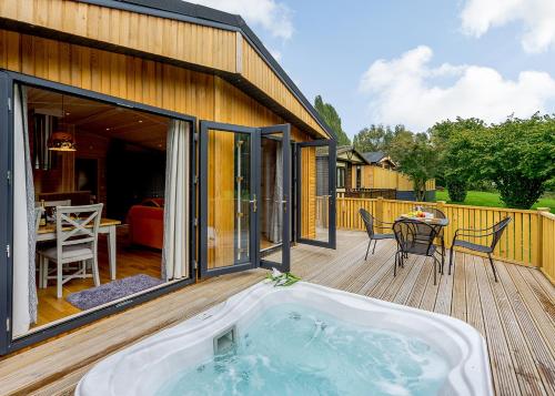 a hot tub on the deck of a house at Ashlea Pools Lodges in Hoptonheath