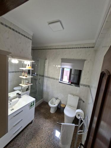 a bathroom with a toilet and a sink and a mirror at Constança House in Corroios