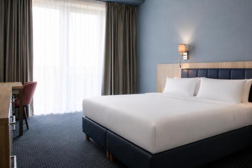 a bedroom with a large white bed and a desk at Aquasolis Spa Hotel in Poľný Kesov