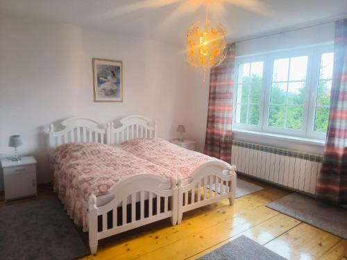 a bedroom with a white bed and a chandelier at Dom Na Fali in Pasym