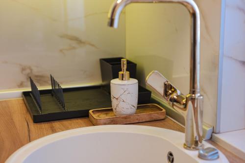 a bathroom sink with a faucet and a candle on a tray at Apartman Centar in Teslić
