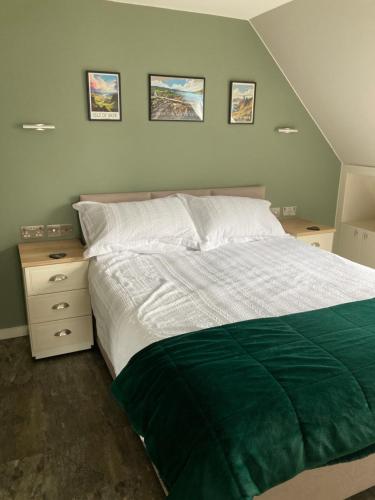 a bedroom with a green and white bed and two night stands at Skyefall Apartment in Uig