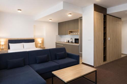 a living room with a blue couch and a bed at Aquasolis Spa Hotel in Poľný Kesov
