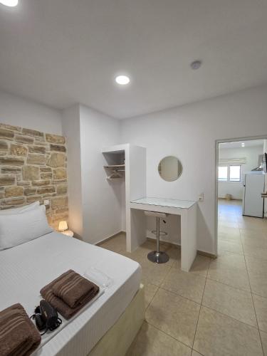 a bedroom with a white bed and a desk at Lithos Home Agia Galini in Agia Galini
