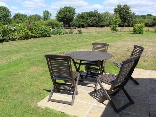 a wooden table with three chairs around it in a yard at Castle House Cottage in Horton
