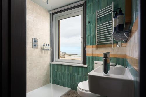 a bathroom with a toilet and a sink and a window at Pedn-Olva in St Ives