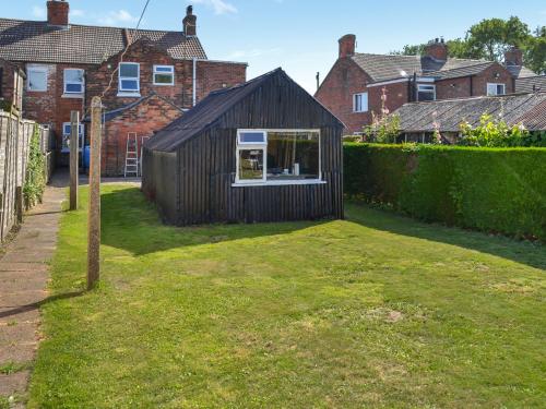 a small black shed in the yard of a house at Billada Cottage in Firsby
