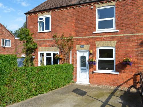 a brick house with a white door and windows at Billada Cottage in Firsby