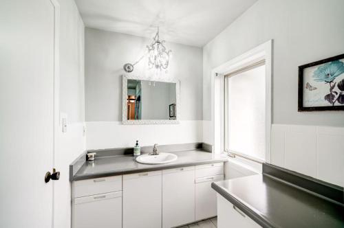 a white bathroom with a sink and a mirror at Butterfly Manor in Niagara Falls