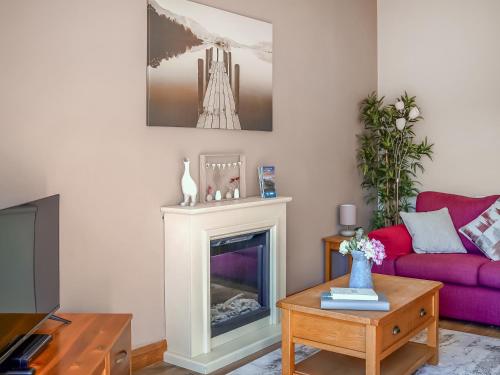 a living room with a fireplace and a purple couch at One The Old Stables in Knitsley