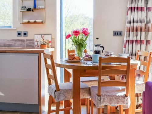 a kitchen with a table with a vase of flowers at One The Old Stables in Knitsley