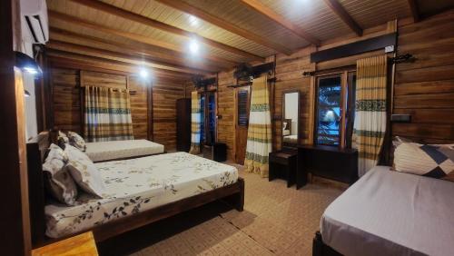 ein Schlafzimmer mit zwei Betten in einer Holzhütte in der Unterkunft Sandy Beach Hotel in Arugam Bay