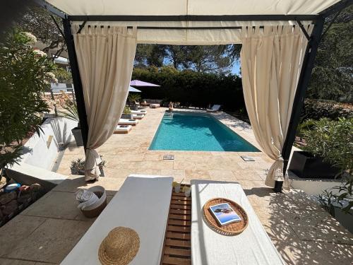 a swimming pool with a canopy and a table with a table sidx sidx at Villa "LES ALIZES" Côté jardin - Bord de mer in Saint-Raphaël