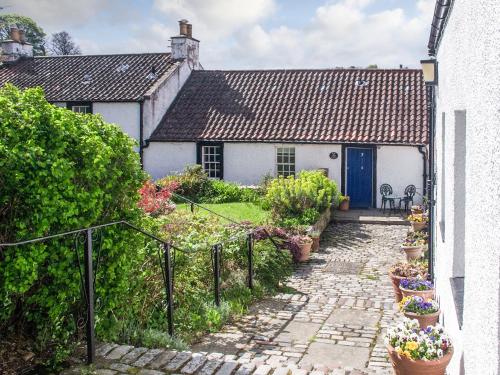 a white house with a blue door and some plants at Quay Cottage in Cramond