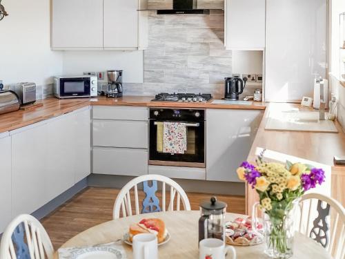a kitchen with a table with a vase of flowers at Two The Old Stables in Knitsley