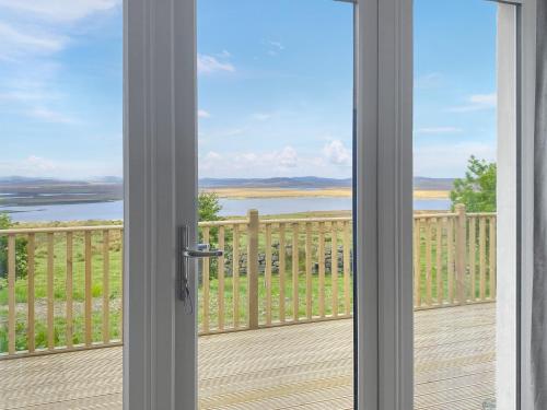 a door to a balcony with a view of the water at Go Ye Cottage in Leurbost