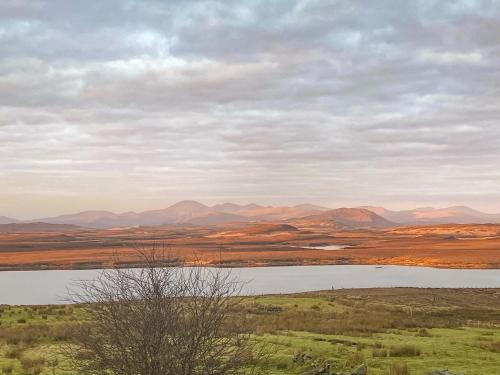 a lake in a field with mountains in the background at Go Ye Cottage in Leurbost