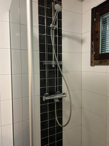 a shower in a bathroom with black and white tiles at Kangaskartano in Keitelepohja