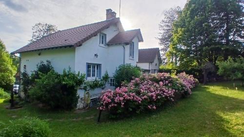 a white house with pink flowers in the yard at Le chant des roses in Giverny