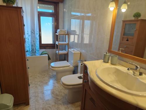 a bathroom with two toilets and a sink and a mirror at La Royana in Vinuesa