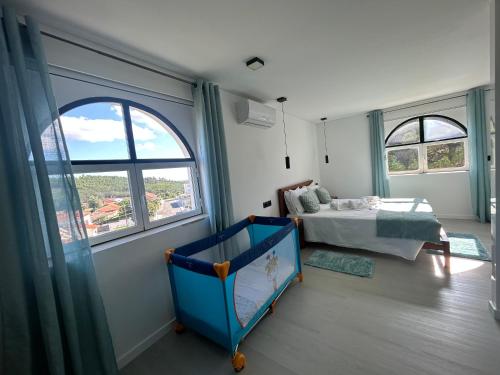 ein Schlafzimmer mit Kinderbett, Bett und Fenstern in der Unterkunft 2Suites in Vila de Rei