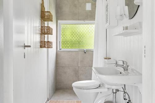 a white bathroom with a toilet and a sink at Charming Cottage Near The Water in Holbæk