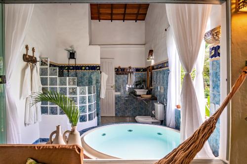 a hammock in a bathroom with a tub at POUSADA CARMELITHA in Trancoso