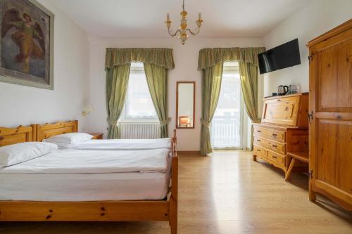 a bedroom with two beds and a dresser and two windows at Hotel Aquila in Cortina dʼAmpezzo