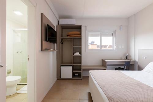 a bedroom with a bed and a sink and a bathroom at Tri Hotel Smart Santa Maria in Santa Maria