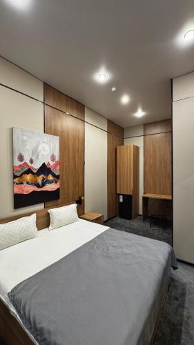 a bedroom with a large bed and a painting on the wall at AIRIS Residence in Almaty