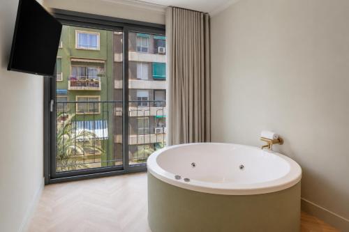 a bath tub in a bathroom with a large window at AT Boutique Alma in Alicante