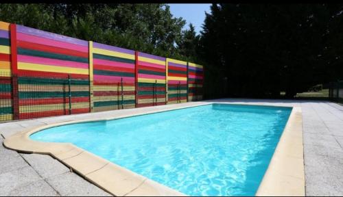 a swimming pool in front of a colorful fence at Camping la Chaumière in Heimsbrunn