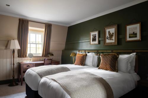 two beds in a hotel room with green walls at The Windmill On The Common in London